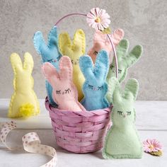 several small stuffed rabbits in a basket with ribbons and flowers on the table next to them