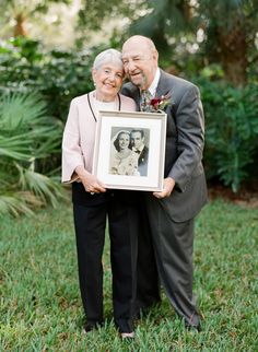 an older couple holding up a framed photo