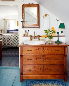 a bathroom with blue flooring and white walls, wooden cabinet under the sink and mirror