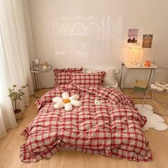 a bed with red and white checkered comforter on it in a bedroom next to a window