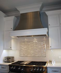 a stove top oven sitting inside of a kitchen next to white cupboards and drawers