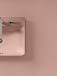 a pink sink mounted to the side of a wall with a faucet and soap dispenser