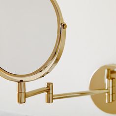 a close up of a mirror on a wall with a metal arm and two circular mirrors