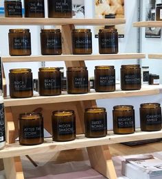 candles are displayed on wooden shelves in front of a mirror and other items for sale