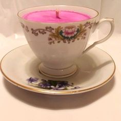 a tea cup with a pink candle in it