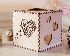 a wooden box with hearts cut out of it sitting on a table next to other decorations