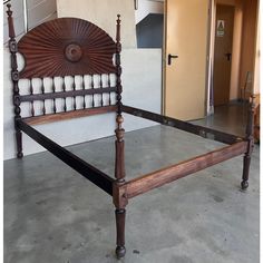 a wooden bed frame with white pillows on it and an open door in the background