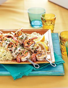 shrimp and rice with lemon wedges are served on a platter next to shot glasses