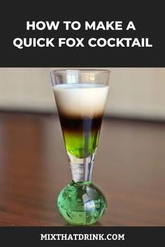 a glass filled with liquid sitting on top of a table next to a green ball