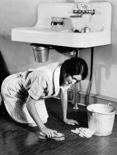 a woman is cleaning the floor with a mop and bucket in front of her