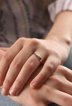 a woman's hand with a gold ring on her left wrist, sitting down