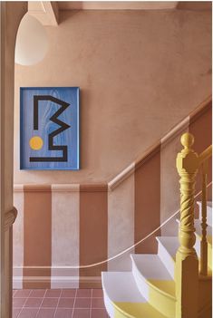 a painting hangs on the wall next to a stair case in a hallway with striped walls