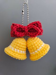 two crocheted bell ornaments hanging from a metal hook on a gray wall with beads