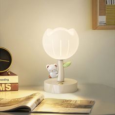 a white lamp sitting on top of a table next to a book