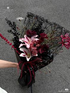 a bouquet of flowers sitting on the ground next to a person's hand holding it