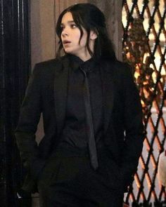 a man with long hair wearing a black suit and tie