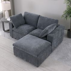 a large gray couch sitting on top of a white rug