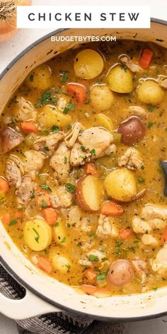 chicken stew with potatoes and carrots in a white pot on top of a table