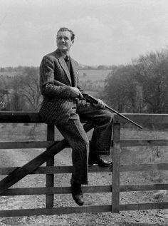 a man sitting on top of a wooden fence