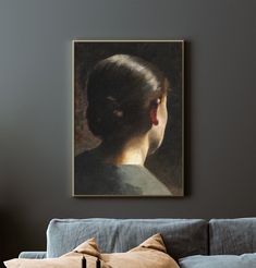 a woman's head in profile, framed on a wall above a couch with pillows