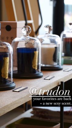 three glass cloches with gold foil on them sitting on a table next to boxes