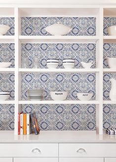 a white book shelf filled with lots of books and bowls on top of it's shelves