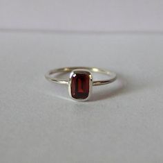 Wir stellen vor: unseren exquisiten Mini Granat Silberring, eine wahre Verkörperung von Eleganz und Raffinesse. Dieses hypnotisierende Stück zeichnet sich durch einen fesselnden roten Stein aus, der zart auf einem makellosen weißen Blatt thront, was einen auffälligen Kontrast schafft, der sicher ins Auge fällt. Dieser Granat Rechteck Ring wurde mit viel Liebe zum Detail gefertigt und verfügt über ein elegantes und zeitloses Design, das ihn zu einer idealen Wahl für jeden Anlass macht. Ob es ein Gold Unique Jewelry, Silver Red Ring, Garnet Silver Ring, Minimalist Crystal Ring With Polished Finish, Minimalist Sterling Silver Crystal Ring For Formal Occasions, Minimalist Gemstone Stackable Rings For Formal Occasions, Minimalist Stackable Gemstone Rings For Formal Occasions, Minimalist Baguette Cut Ring With Polished Finish, Minimalist Emerald Cut Sterling Silver Birthstone Ring