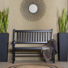 a wooden bench sitting next to two planters and a round mirror on the wall