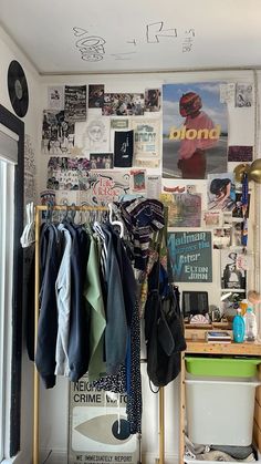 a cluttered room with clothes hanging on the wall and various posters on the wall