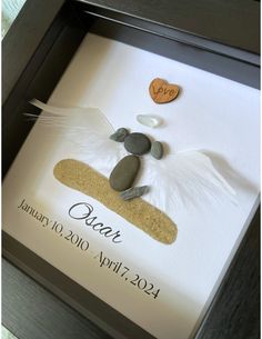 a pebble and stone wedding gift in a shadow frame with the date written on it