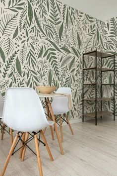 three chairs and a table in front of a wall with green leaves on the wall