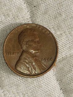 an old penny is laying on a white cloth