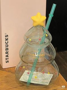 a clear glass christmas tree with a star on top and a green straw sticking out of it