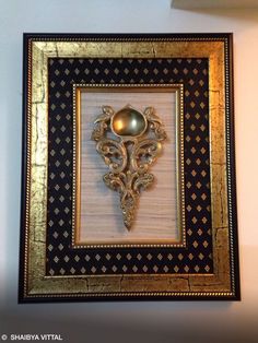 an ornate gold and black frame with a golden ball on it