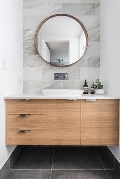 a bathroom with a large mirror above the sink and wooden cabinetry on the wall