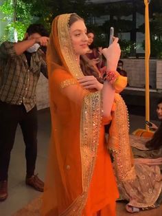 a woman dressed in an orange outfit taking a selfie