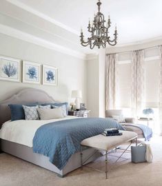 a bedroom with a large bed, chandelier and two pictures on the wall