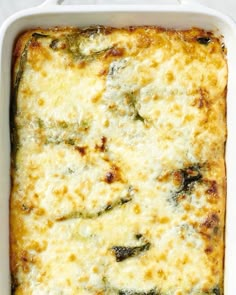 a casserole dish with cheese and spinach in it on a white surface