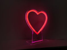 a heart shaped neon sign sitting on top of a table