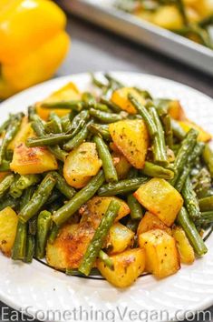 a white plate topped with green beans and potatoes