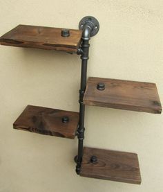 three wooden shelves mounted to the side of a wall with metal pipe holders on them