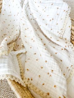 an unmade bed with white sheets and gold stars on it's edges, next to a wicker basket