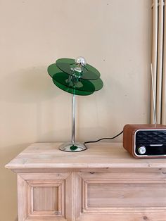 a table lamp sitting on top of a wooden dresser next to a radio and clock