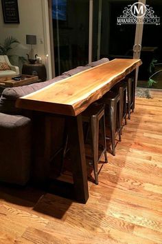 a long wooden table sitting in the middle of a living room next to a couch