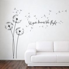 a white couch sitting in front of a wall with a dandelion decal on it