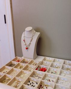 a white display case filled with lots of different necklaces and earrings on top of a table