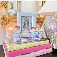 a stack of books sitting on top of a table next to a lamp and vase