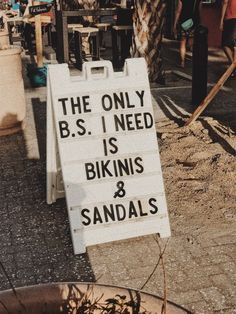 the only b s i need is bikinis and sandals sign in front of an outdoor cafe