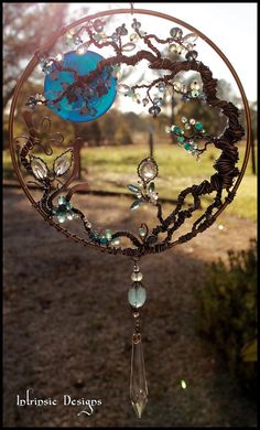 a wind chime hanging from the side of a tree with beads and leaves on it