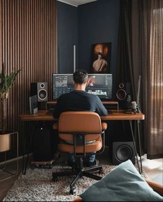 a man sitting at a desk in front of a computer monitor and sound equipment on it